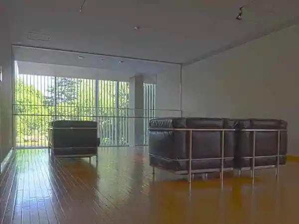This photo shows sofas on the east side of the reference room on the second floor of the Gallery of Horyuji Treasures. The sofas are positioned in front of a glass wall that faces the garden, offering a stunning view of the garden and pond in front of the Treasure House. These sofas were designed by renowned architect Le Corbusier (1887-1965).