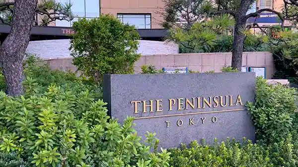 ザ・ペニンシュラ東京の入り口の石碑の写真です。縦1m、横2mのグレーの石材に金色の文字で「 THE PENINSULA TOKYO」と描かれています。
