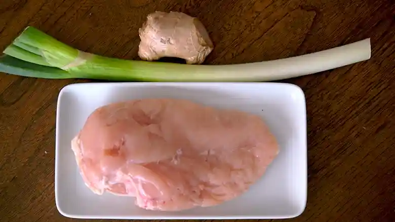 海南チキンライス釜飯の材料の写真です。鶏むね肉と長ネギ、生姜が並んでいます。