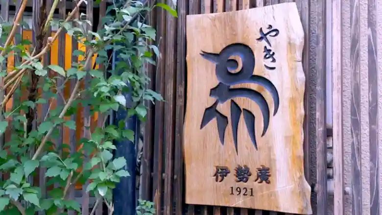 伊勢廣京橋本店の木製の看板の写真です。ロゴマークの鳥の絵が刻み込まれています。看板の下方には、伊勢廣1921と書かれています。伊勢廣は1921年、大正10年に創業されました。