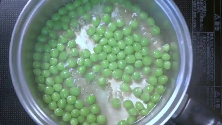 鞘の煮汁で豆を煮ている写真です。豆が鮮やかな緑色になっています。