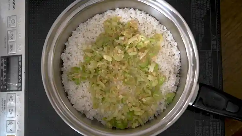 ご飯とネギだれをステンレス製の鍋に入れた写真です。白いごはんの上のネギだれの緑色が鮮やかです。