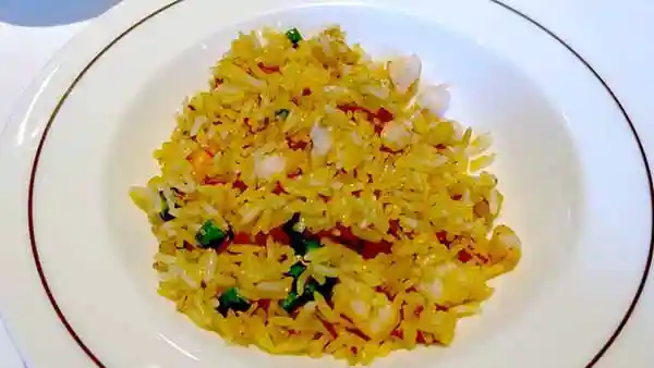 海老と秋栗のチャーハンの写真です。米はジャスミンライスで細長い形をしています。黄色く調理されたご飯の中に赤いエビと白い秋栗、緑色のネギが混ざっています。