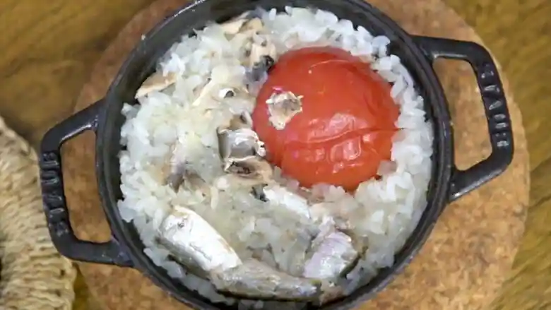 炊きあがった「オイルサーディンのイタリアン釜飯」の写真です。トマトが鍋の端に移動しています。ご飯の表面にイワシが見えます。
