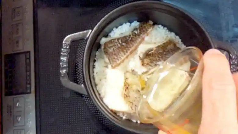 米と焼いた鯛を入れた鍋に200mlの水を加えている写真です。