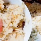 炊きあがった「北海道ホッキ釜飯」を白い茶碗にもった写真です。ご飯は薄茶色、ホッキ貝はピンク色をしています。