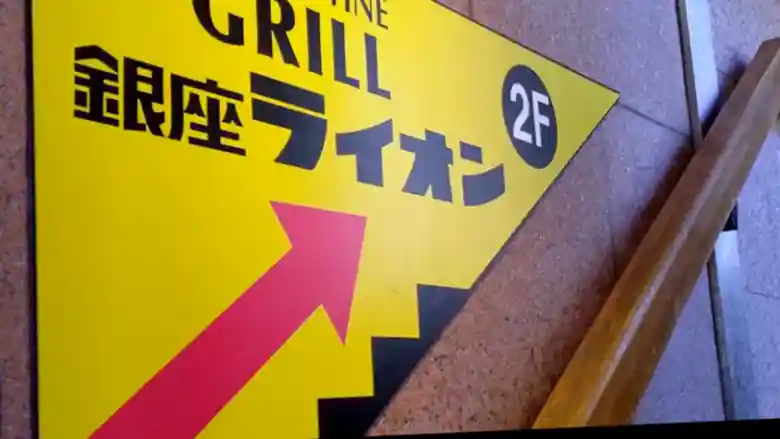 「BEER & WINE GRILL」の看板です。黄色い板に黒い文字で「GRILL 銀座ライオン」と書かれています。