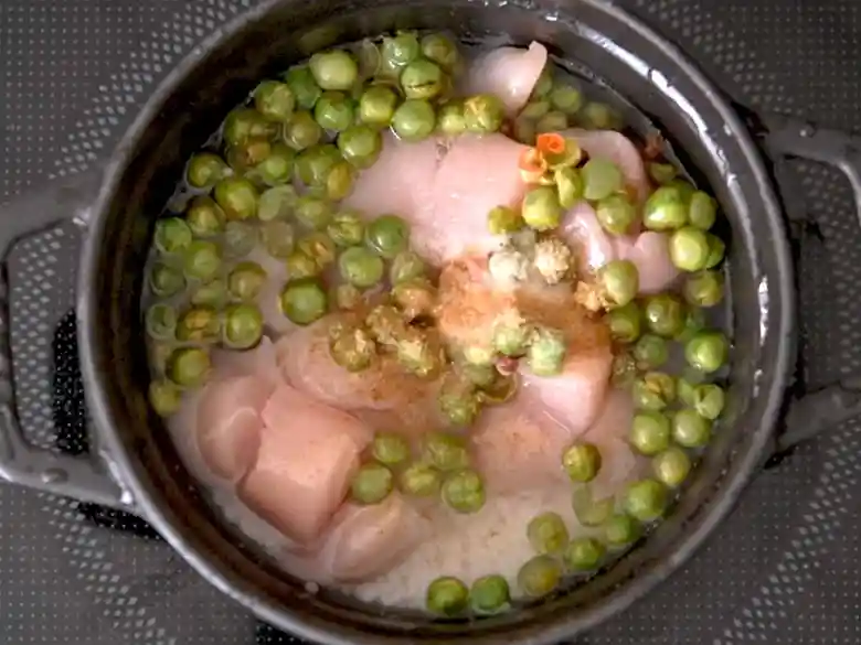 黒い鍋に米と麻辣青豆、ささみ、塩、コンソメ顆粒を加えた写真です。