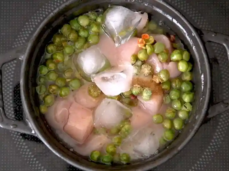 黒い鍋に米と麻辣青豆、ささみ、塩、コンソメ顆粒を加えた写真です。氷もたされています。