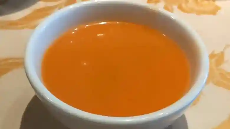 白いカップにはいったスープの写真です。トマトの色をしたスープです。