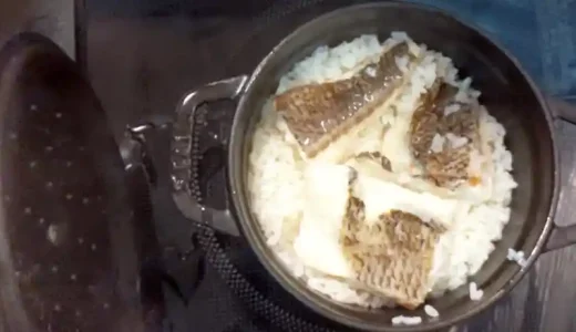 STAUB（ストウブ）鍋に入れた米の上に、焼いた鯛の切り身を並べた写真です。鍋は直径は14cmで黒い色をしています。