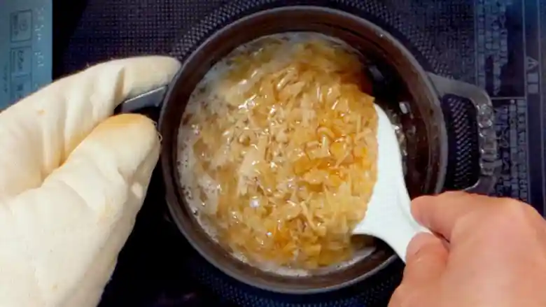 お米を白いしゃもじでかき混ぜている写真です。なめ茸とツナがよく混ざっています。