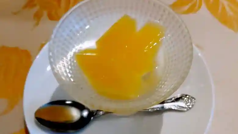 デザートのオレンジゼリーの写真です。格子模様のガラスの器に入っています。