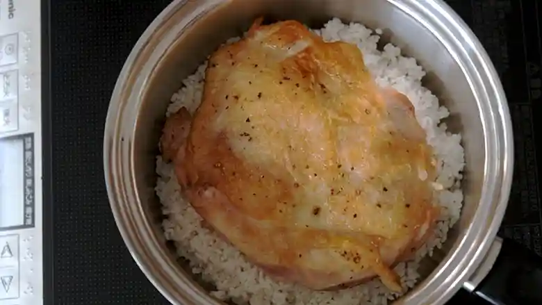 炊きあがった「鶏ときのこの炊き込みご飯」の写真です。ご飯は薄茶色に染まり、お焦げもできています。