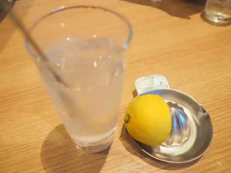 生搾りレモンサワーの写真です。サワーのわきに、レモンと絞り器が置かれています。