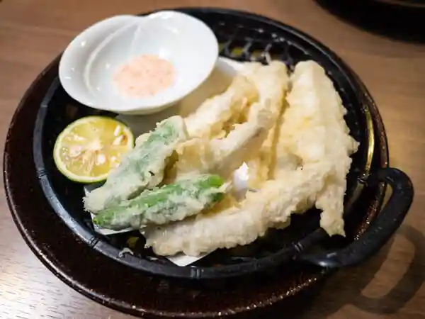 わかさぎの天ぷらの写真です。すだちとししとうが添えられています。梅塩をつけて食べます。