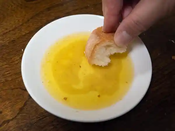 フライパンに残ったソースにパンを浸して食べている写真です。ソースにはマテ貝の旨みが溶け込んでいます。