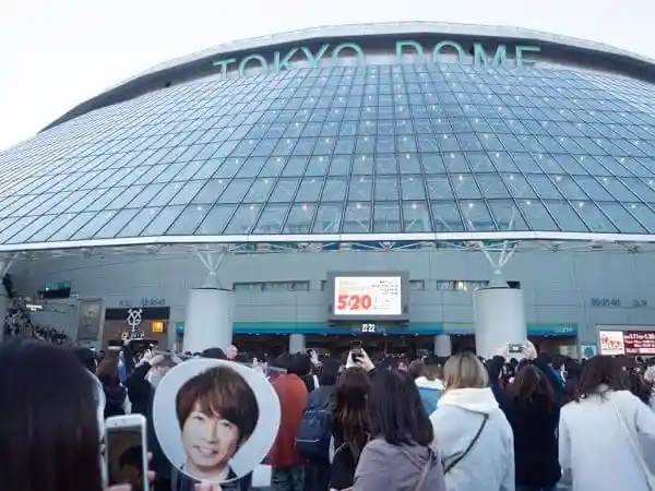 2018年12月24日の嵐のコンサートが始まる直前の東京ドームの写真です。ドームの正面には「5×20 ARASHI Tour」と書かれた大きな看板が掲げられています。この日は相葉くんの誕生日でした。ファンが持つ相葉くんの写真が貼られた大きなうちわが写っています。