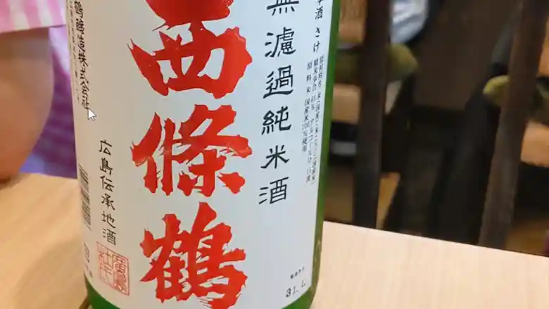  西條鶴 無濾過純米酒（西條鶴酒造、広島） のボトルの写真です。白いラベルに赤い文字で「西条鶴」。果実のような香りに、ワインのような甘み。広島のお酒は美味しいです。