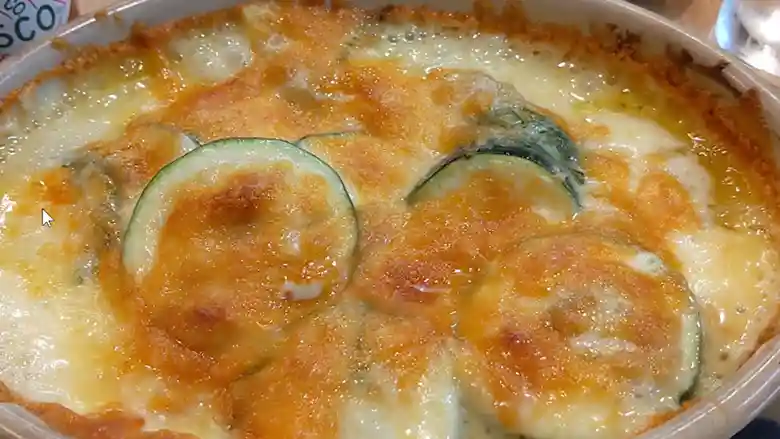 新ジャガとズッキーニ、アンチョビのチーズ焼きの写真です。チーズに焦げ目がついて食欲をそそります。