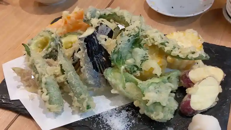 夏野菜の天ぷらの写真です。野菜はゴーヤ、オクラ、なす、にんじん、さつまいも、とうもろこし、大葉、なす、みょうがです。
