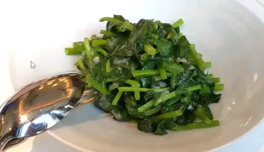 台湾豆苗のガーリック炒めの写真です。白い皿に色鮮やかな緑色をした豆苗が盛られています。豆苗はシャキシャキした食感でにんにくがほのかに香ります。