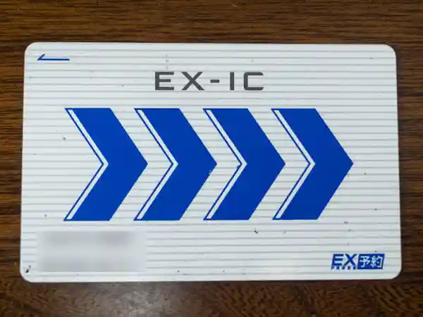 EX-ICカードの写真です。白い背景に青い矢印が描かれています。このカードを新幹線改札機にタッチすると「EXご利用票」が発券されるので、これを受け取って入場します。