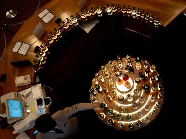 サントリー山崎蒸留所ウイスキー館内に設けられたテイスティングカウンターを真上から撮影した写真です。円形のカウンターに置かれたボトルがライトアップされて幻想的な雰囲気です。