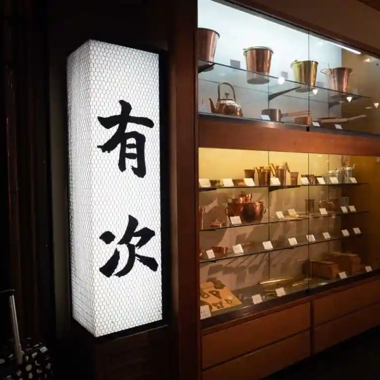 有次の看板の写真です。白地に黒い文字で有次を書かれています。お店は京都の錦市場にあります。