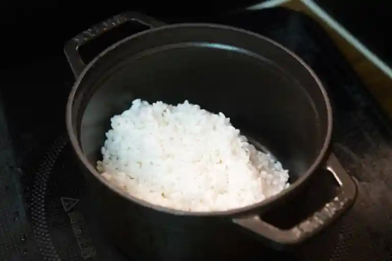 黒い鍋に米1合を入れた写真です。鍋は鋳鉄製で、直径14cm、高は10cmです。
