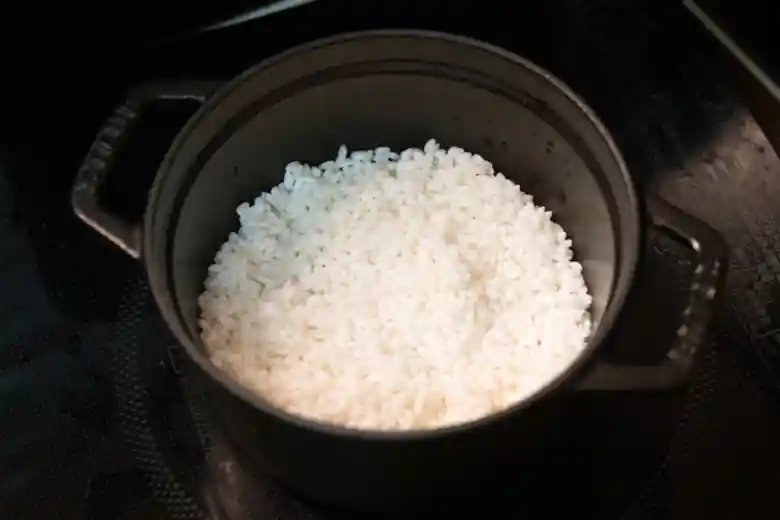 黒い鋳鉄製の鍋に入ったお米の写真です。お米の量は1合で、2時間水に浸していました。鍋の直径は14cm、高さは10cmです。