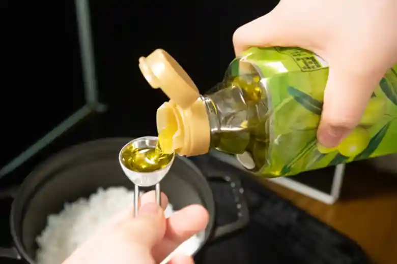 オリーブオイルを大さじに注いでいる写真です。オリーブオイルは500ミリリットルのペットボトルに入っています。