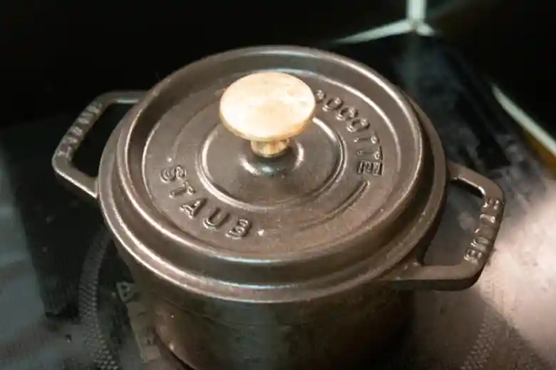鍋に蓋をして強火で加熱している写真です。鍋は黒色ですが、鍋の蓋の取っ手は金色です。