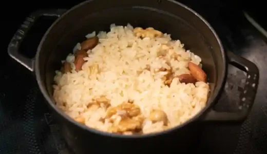炊き上がったミックスナッツ釜めしの写真です。鍋の蓋を取って写しました。薄い茶色に染まったご飯にナッツが混じって見えます。