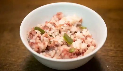 白い茶碗にコンビーフ釜飯をよそった写真です。コンビーフの赤色とピーマンの緑色が鮮やかです。ほぐしたコンビーフがご飯によく混ざっています。