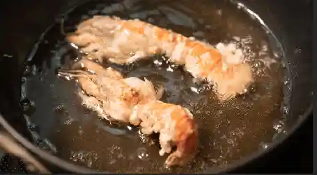 穴ジャコを天ぷら鍋で揚げている写真です。２本の穴ジャコが調理されています。体表は赤い色に変わっています。180度で3分間揚げると完成です。