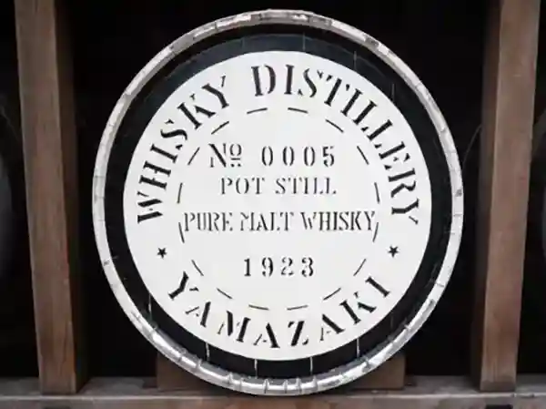 This photo shows a whiskey barrel. This barrel is stacked by the entrance of the whisky pavilion at the Suntory Yamazaki distillery." NO.0005 PURE MALT WHISKY 1923" is engraved on the bottom of the barrel.