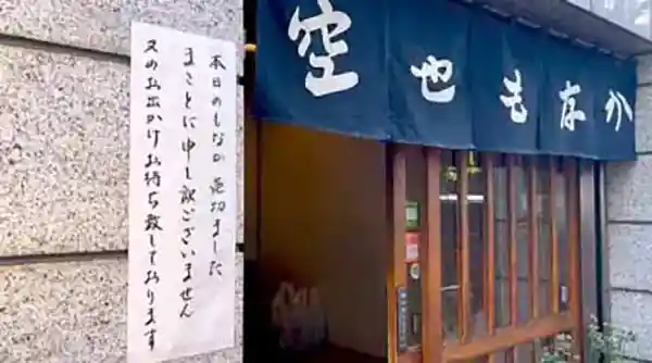 The photo shows the entrance to Kuuya on Namiki-Dori in Ginza 6-Chome. The dark blue curtain has "Kuuya Monaka" written in white letters.