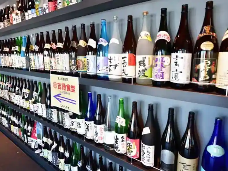 吉池食堂へ向かう通路の写真です。壁一面に日本酒の瓶が並べられています。
