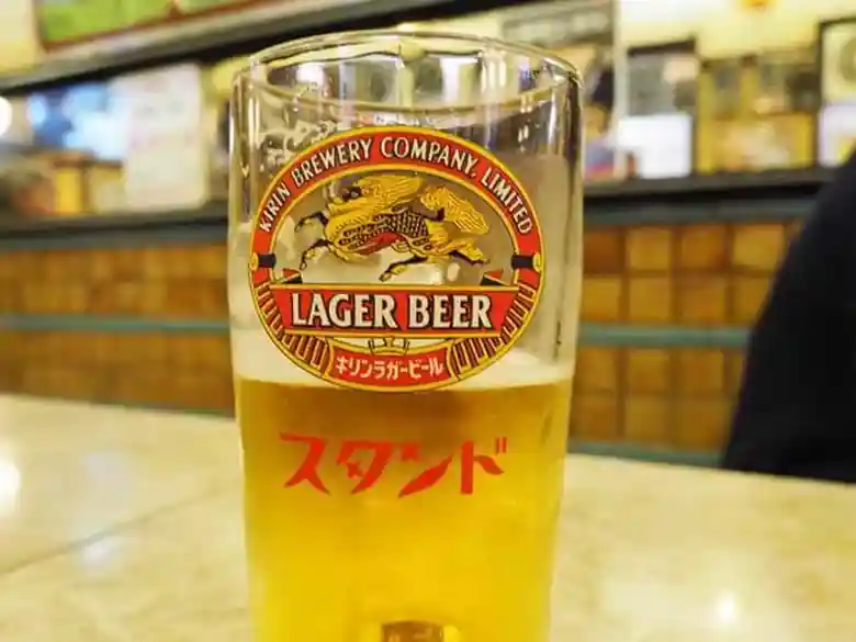 グラスに注がれた生ビールの写真です。ビールはキリンラガーで、グラスには赤い字でスタンドと書かれています。