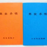 国民年金手帳の写真です。表紙の色がオレンジとブルーの手帳が並んでいます。オレンジ色の手帳は1974年11月から1997年1月まで発行されました。その後は現在までブルーの手帳が使われています。