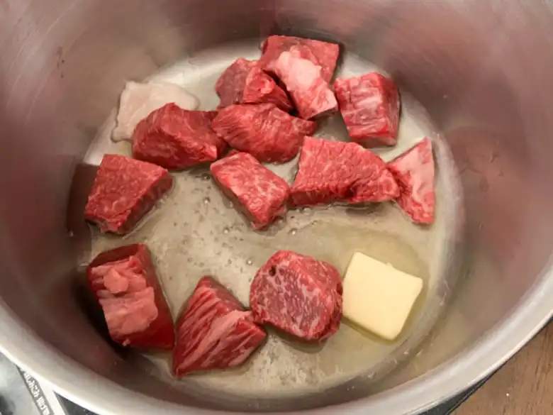 バターとオリーブ油を入れた鍋で牛肉を炒めている写真です。牛肉の表面が少し焦げ始めています。