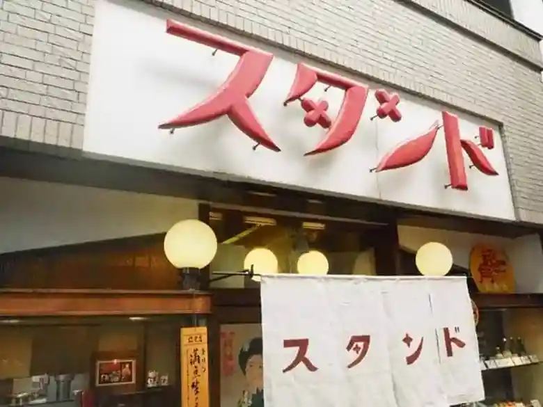 新京極にある京極スタンドというレストランの写真です。入り口には白地の看板と暖簾がかかっています。ともに赤い字でスタンドと書かれています。
