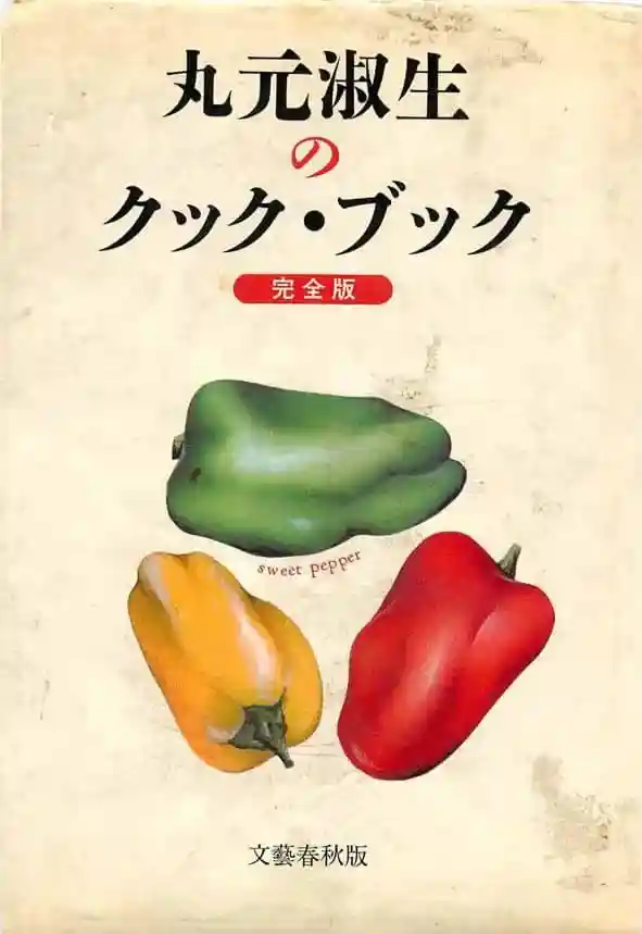 丸元淑生のクック・ブックという本の表紙です。緑、黄、赤色のピーマンの絵が描かれています。