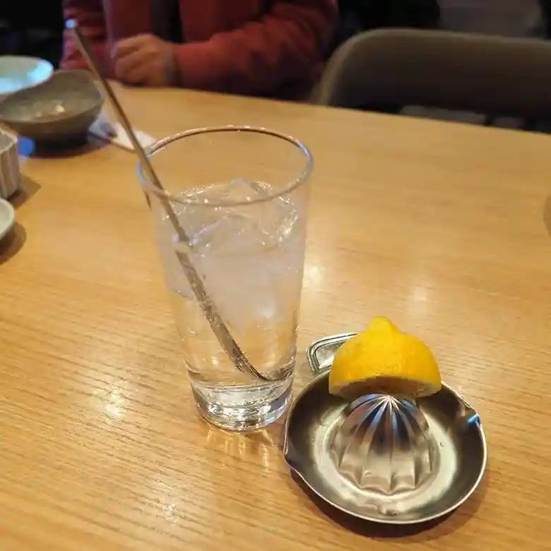 生レモンサワーの写真です。焼酎と氷が入ったグラスの脇に半分に切られたレモンが置かれています。