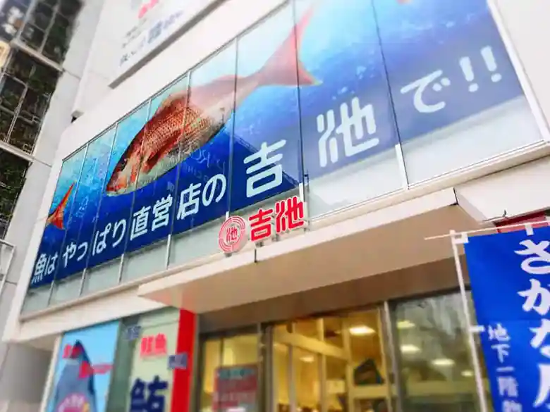 吉池ビルの看板です。大きな鯛の絵の下に「魚はやっぱり直営店の吉池で」と書かれています。