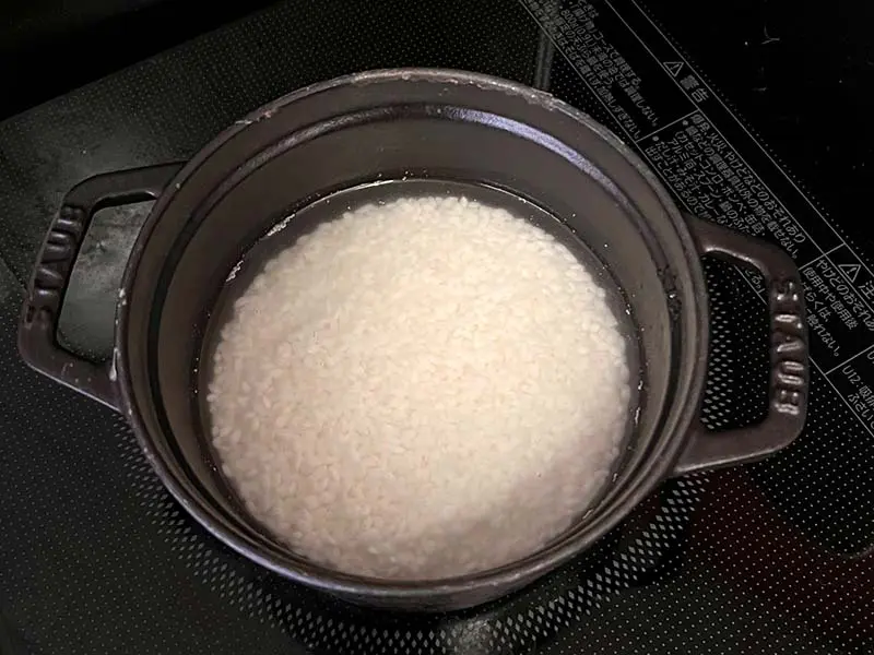 浸漬米の写真です。ストウブ鍋の中で米が水につかっています。洗った米を1時間以上水につけて吸水させました。