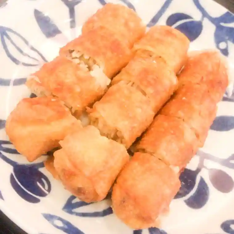 This photo shows spring rolls served on a white plate. The spring rolls are cut into bite-sized pieces. In addition to bamboo shoots, the spring rolls are filled with shrimp, shiitake mushrooms, green onions, and pork.
