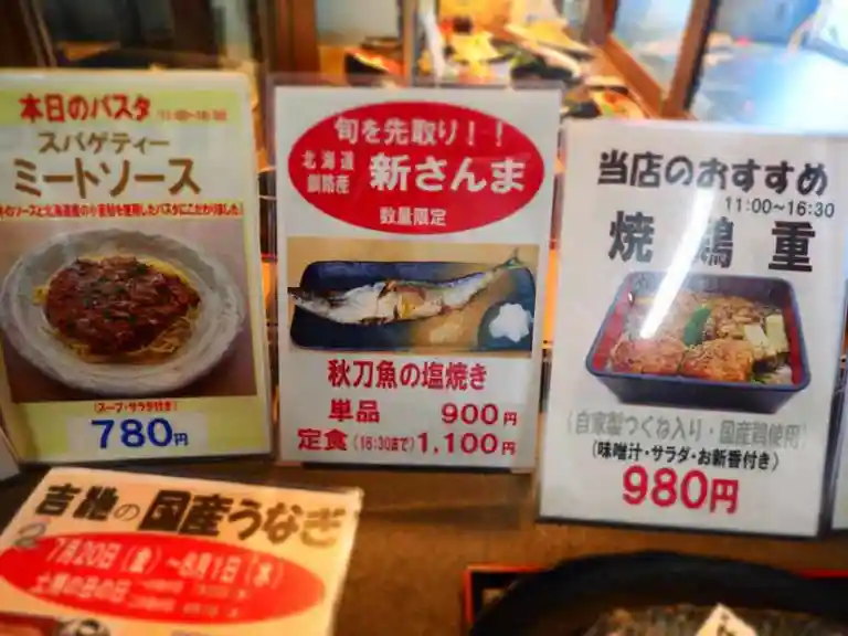 吉池食堂の入り口に置いてあるメニューの写真です。秋刀魚の塩焼きと焼鶏重が写真入りで紹介されています。