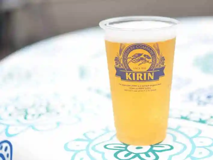 野外のテーブルの上に置かれた生ビールの写真です。ビールはプラスチックのコップに注がれています。銘柄はキリン一番搾りです。
